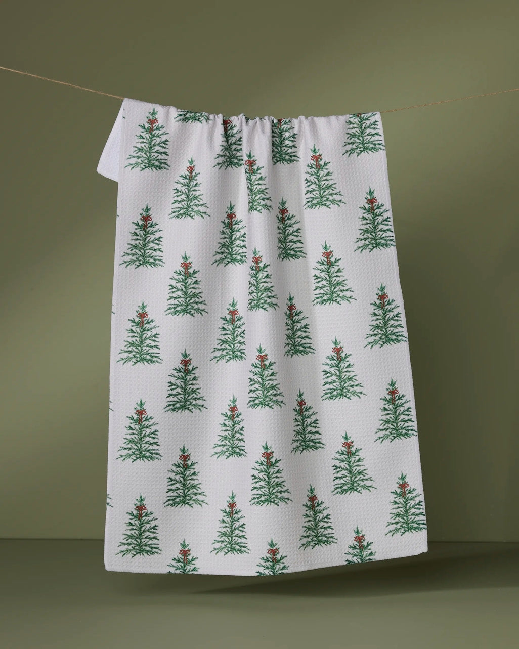 Holiday tea towel with waffle weave construction in festive red featuring a white snowflake pattern.