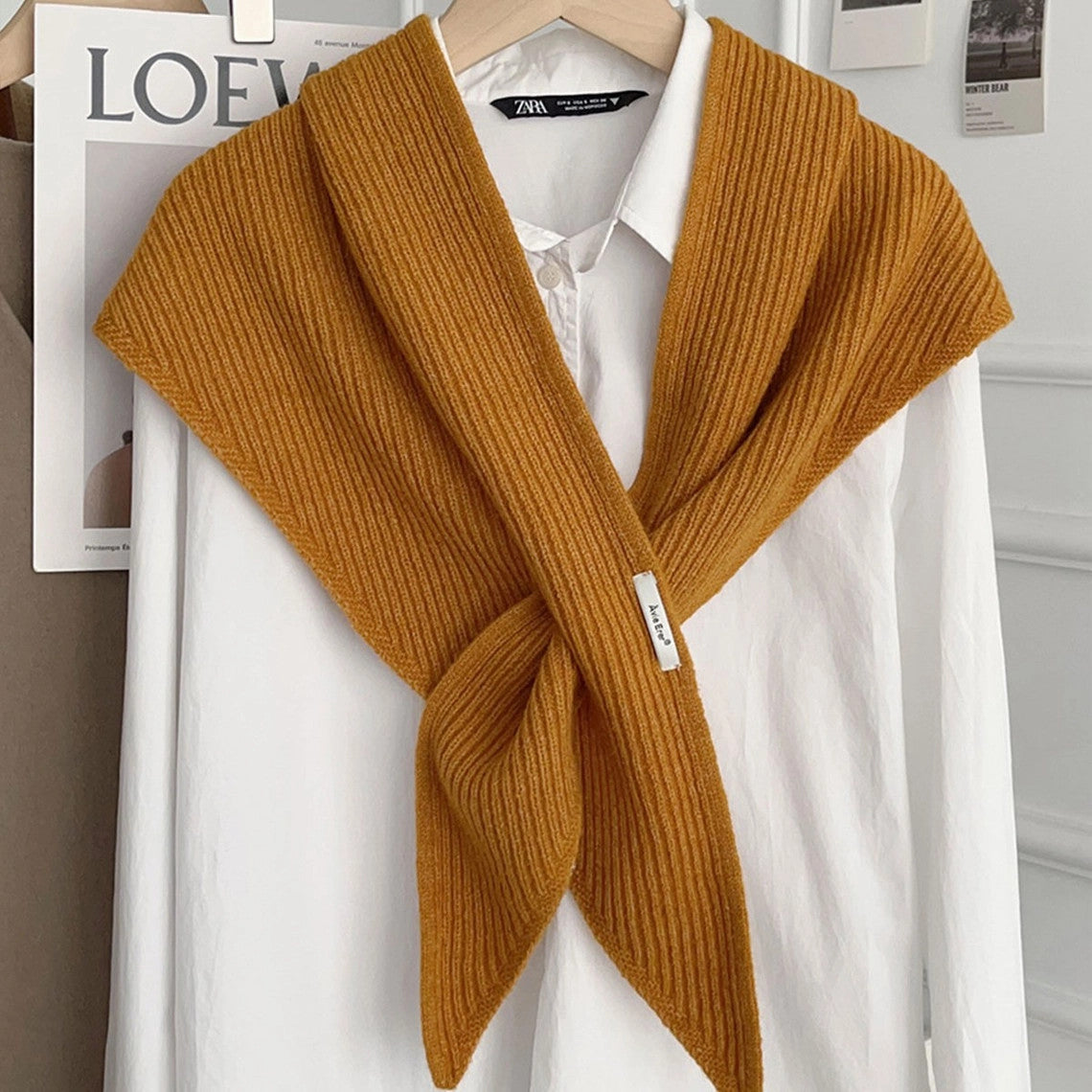 Mustard yellow knitted solid cross triangle shawl draped over a white button-down shirt.