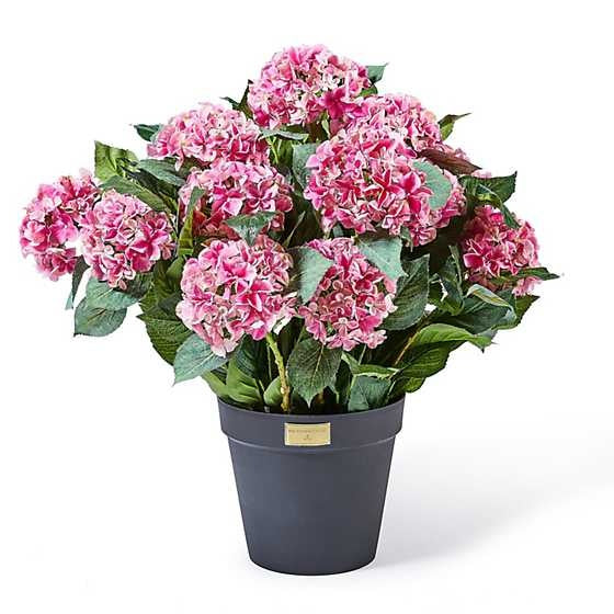 Black plastic pot containing pink artificial hydrangea florals in a full silhouette.