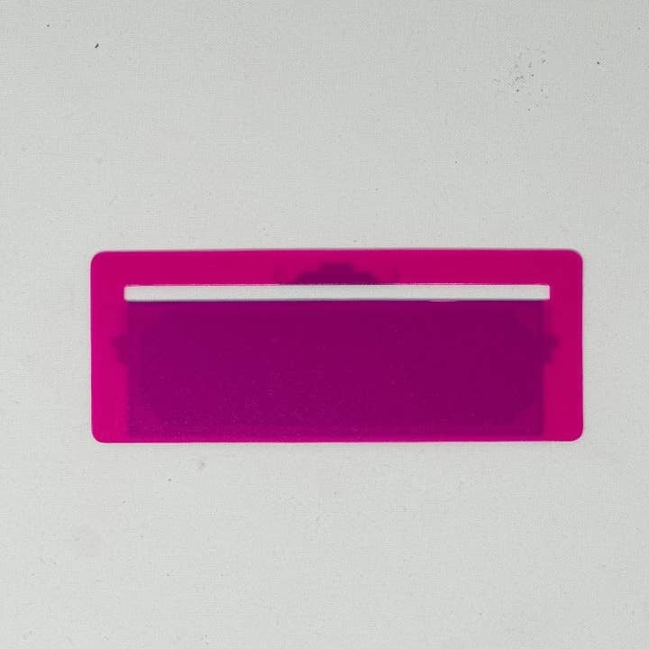 Pink plastic Mahjong line finder tool with a circular cutout shape.