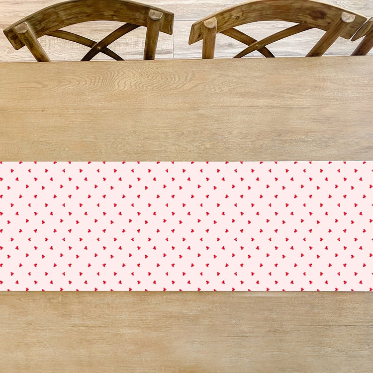 White paper table runner with a ditsy hearts pattern in soft pastel colors.