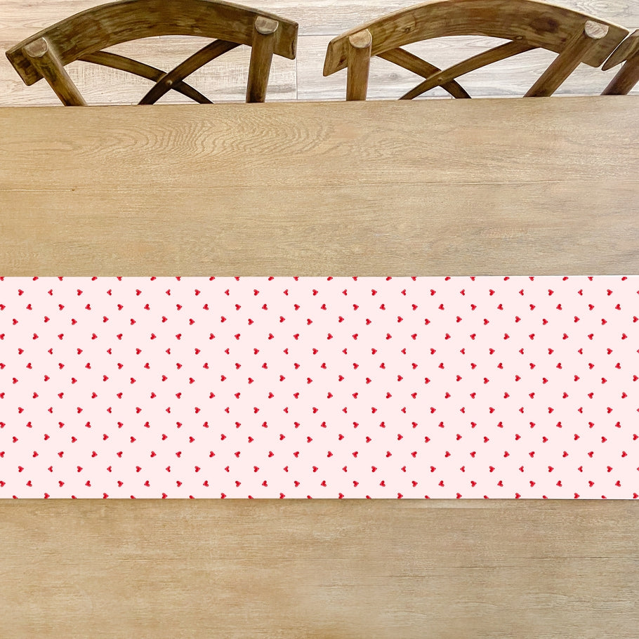 White paper table runner with a ditsy hearts pattern in soft pastel colors.