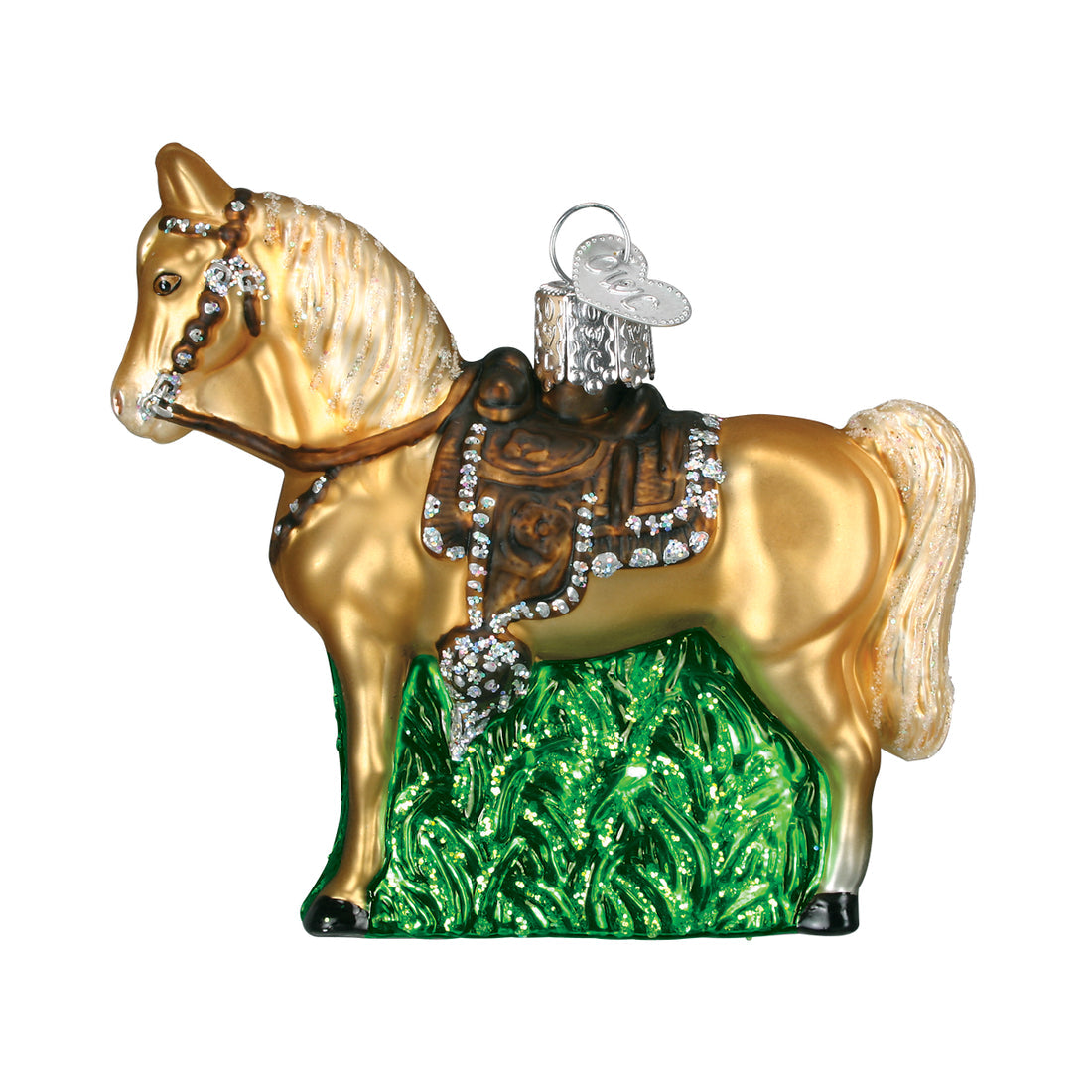 Glass western horse ornament with a gold body, brown saddle, and silver glitter accents on grass.