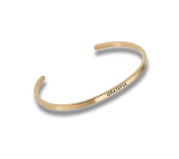 Gold-toned metal cuff bracelet engraved with the word GRATEFUL in a simple, clean font.