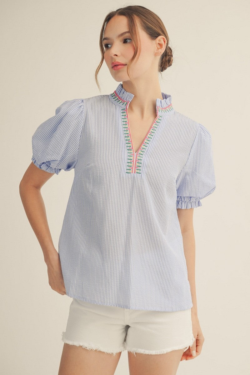 Woman wearing a small Celine textured stripe top with puff sleeves, ruffled neckline, and embroidery accent.