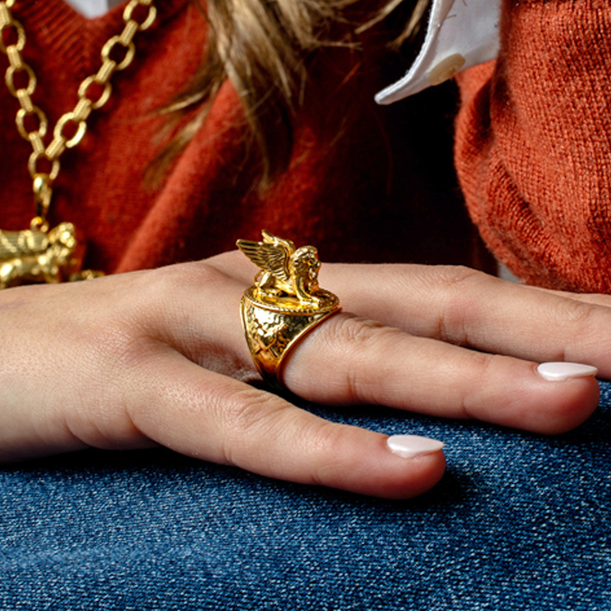 A person wearing the gold Lionheart Ring, featuring a sculpted winged lion on a textured band.