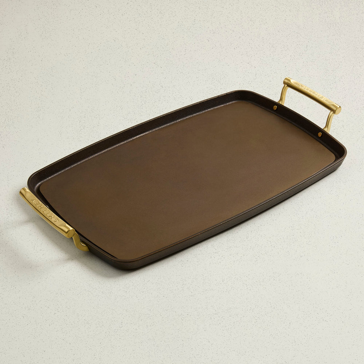 Rectangular cast iron double burner griddle with smooth cooking surface and brass handles.