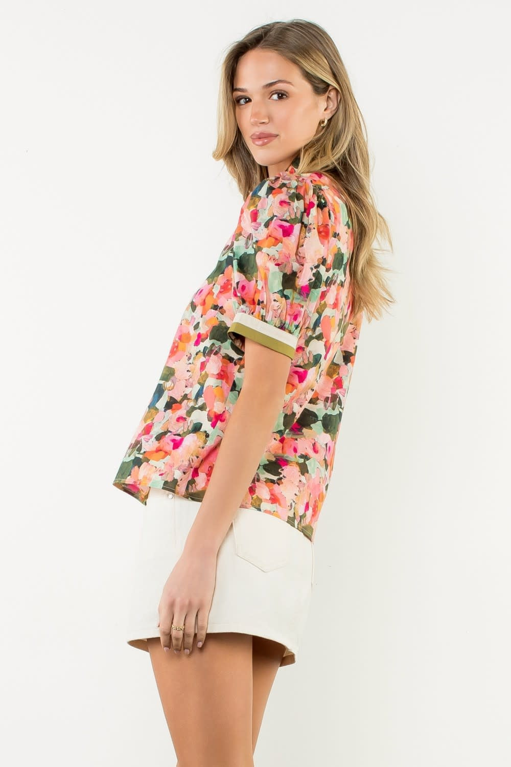 Side view of a white cotton women's top with pleated collar and puff sleeves.