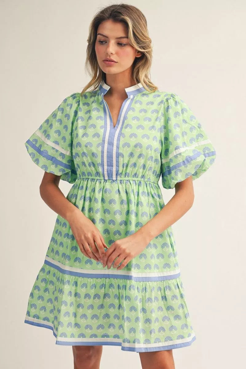 Boho floral print cotton dress with puff sleeves, tiered skirt, standing neckline, and side pockets in black.