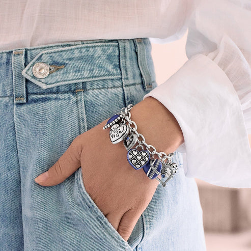 A person wearing the One Heart Link Charm Bracelet with silver and blue heart charms.