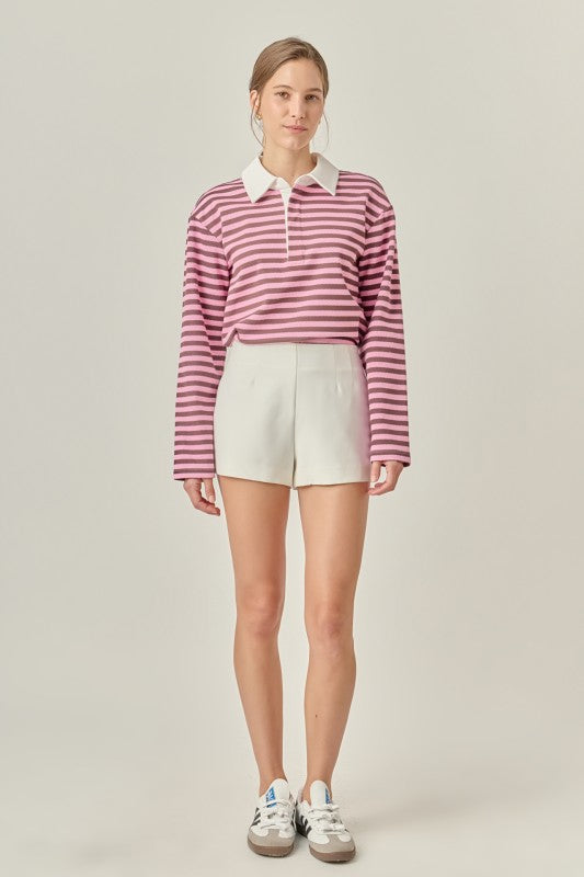 Pink striped rugby polo shirt with classic collar, long sleeves, drop shoulders, and soft knit fabric in a relaxed modern fit.