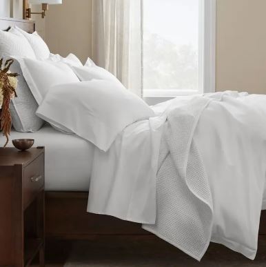 Signature Hemmed Sheet Set in King White on a bed with matching pillows and a textured blanket.