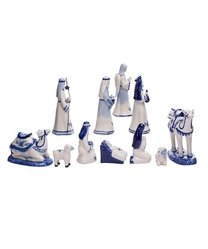 White porcelain nativity set with Delft blue designs featuring Baby Jesus, Mary, Joseph, Wise Men, an angel, camels, and sheep.