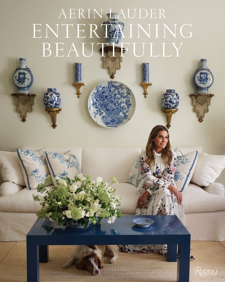 Book cover of Entertaining Beautifully by Aerin Lauder featuring a woman on a white sofa.