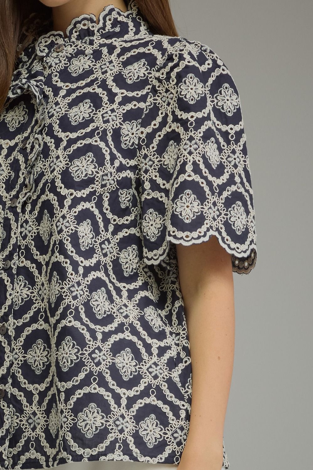 Close-up of a navy blue Amalia top with white geometric embroidery and scalloped puff sleeves.