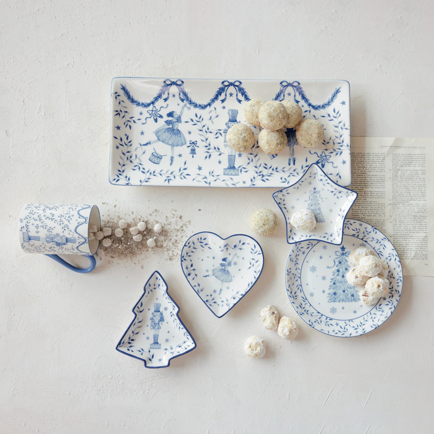 White and blue ceramic holiday dishes in heart, star, and tree shapes with nutcracker designs.