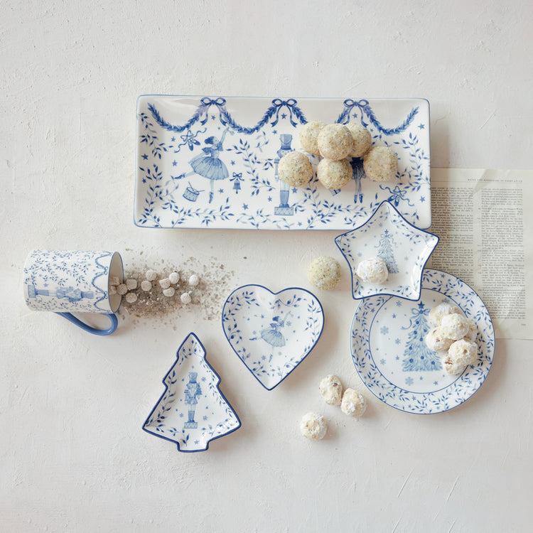 White and blue ceramic holiday dishes in heart, star, and tree shapes with nutcracker designs.