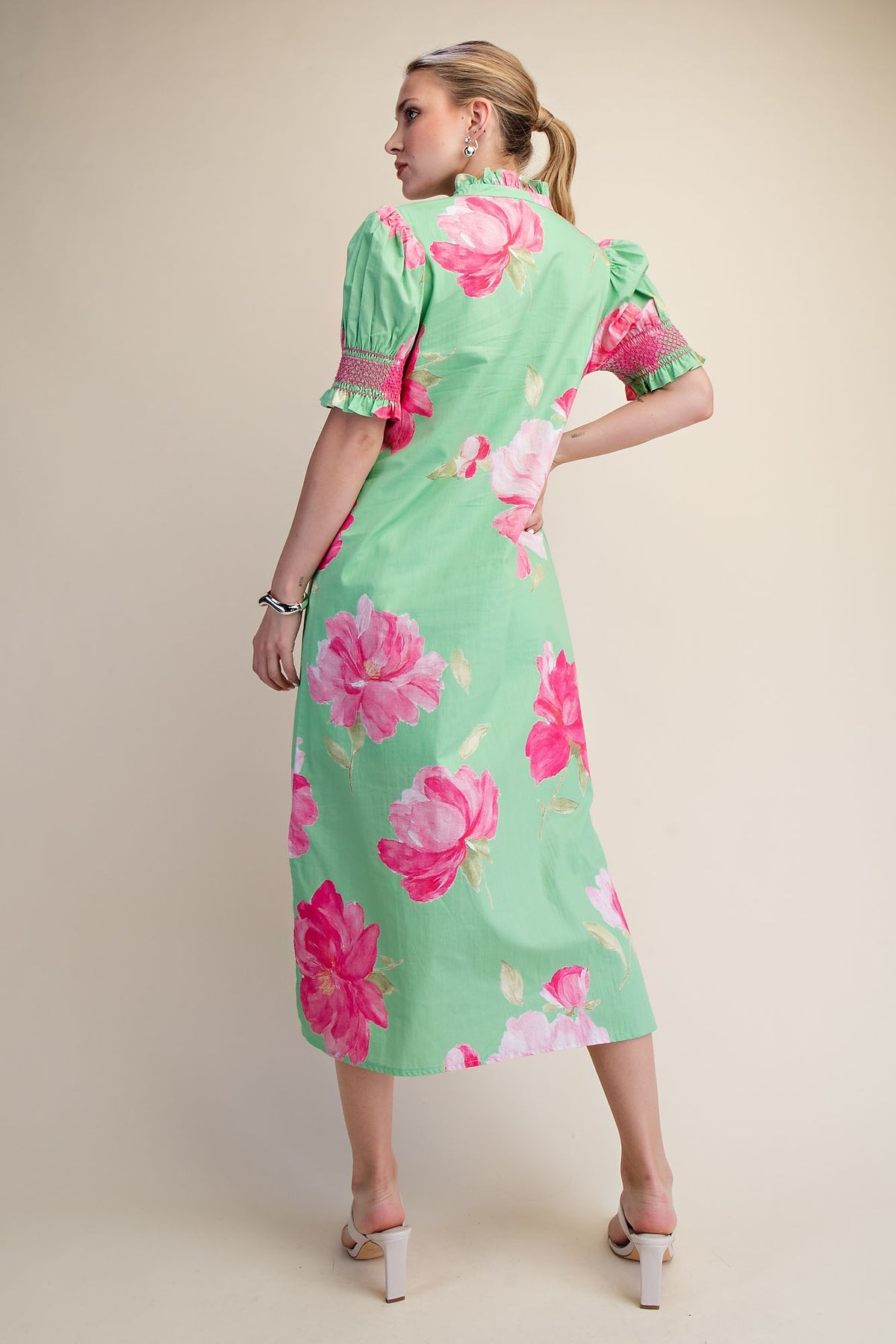 Back view of a green midi dress with pink floral print, puff sleeves, and a ruffled neck.