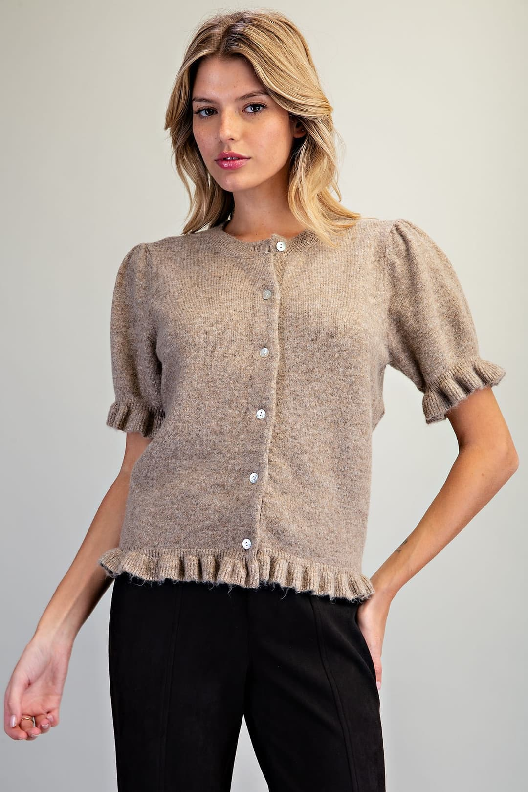 Woman wearing a tan Ezra Ruffle Trim Short Sleeve Cardigan with puff shoulders and black pants.