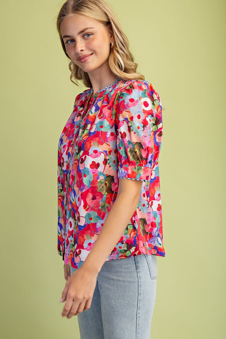 Woman wearing a Sophia Bold Floral Button Down Blouse with ric-rac trim and light wash jeans.