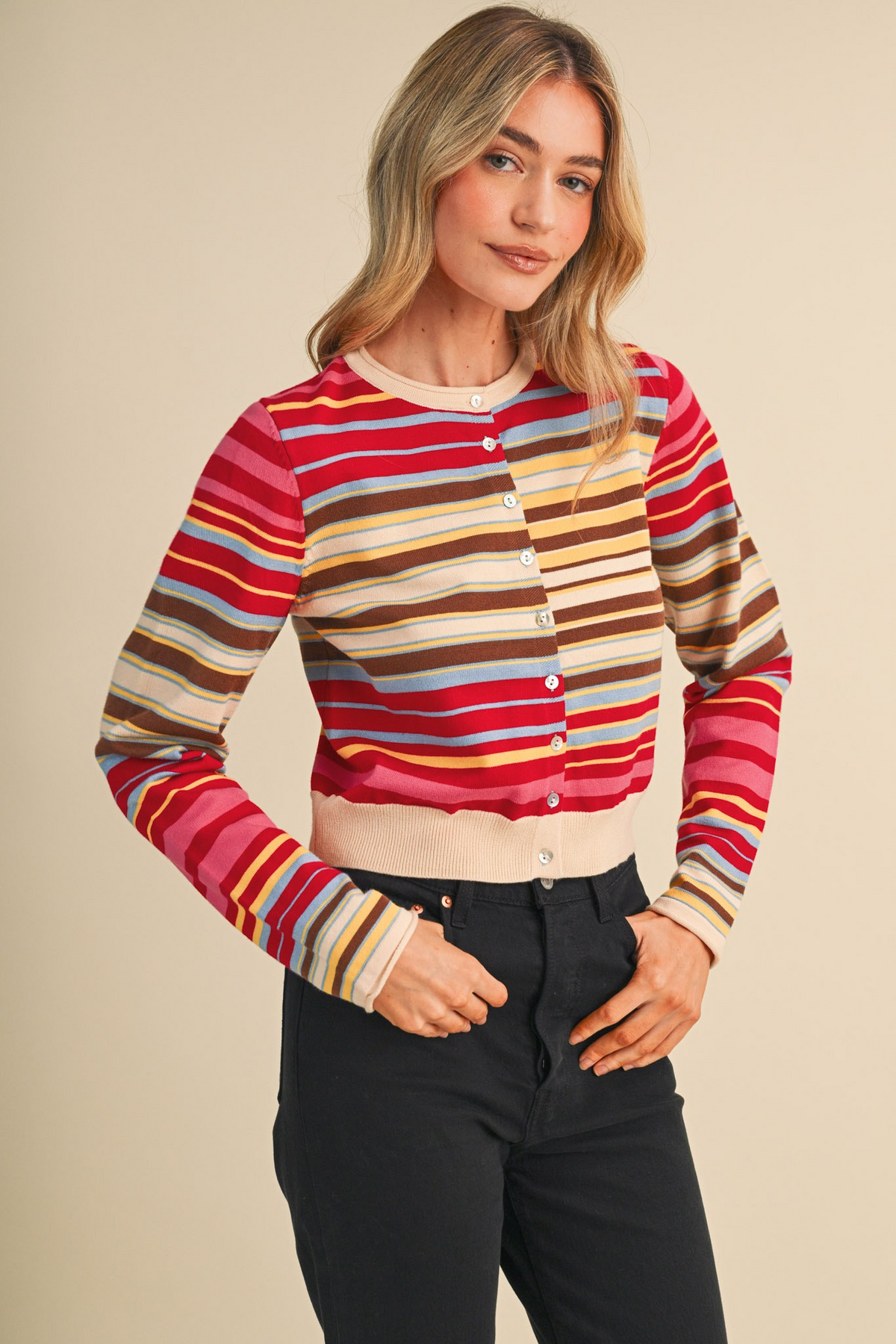 Woman wearing a Vivi multi-color striped sweater cardigan with a button-front and black jeans.