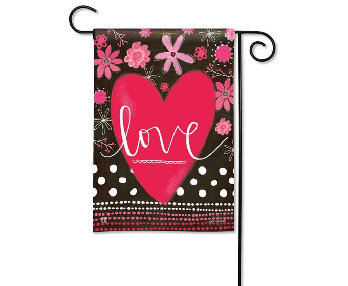 Garden flag with a large pink heart and the word "love" in white script, surrounded by pink flowers and white polka dots.