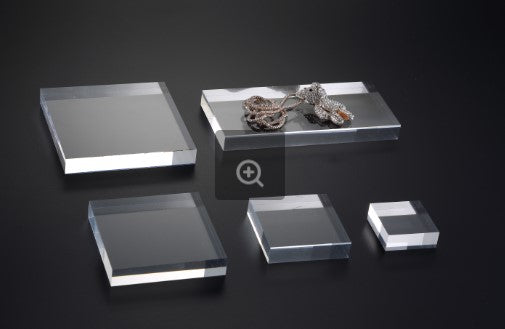 Clear acrylic square display block on a black background.