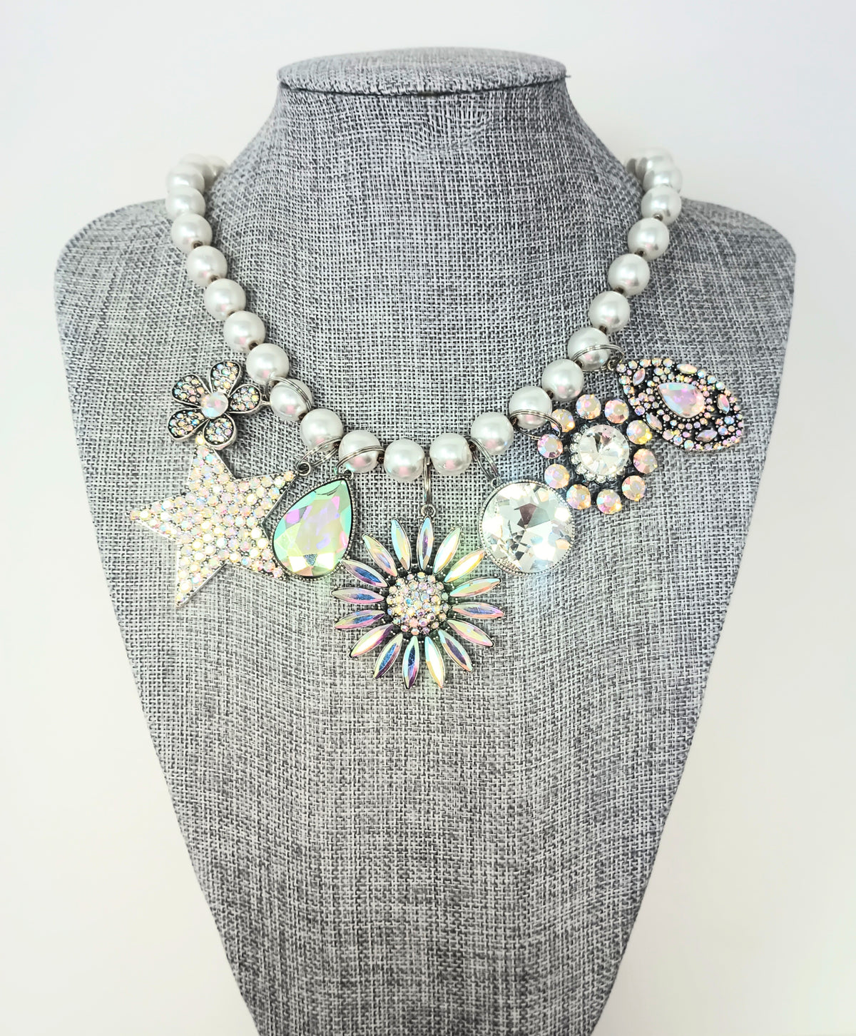 18-inch pearl necklace featuring seven rhinestone-encrusted charms in star, flower, and gem shapes.