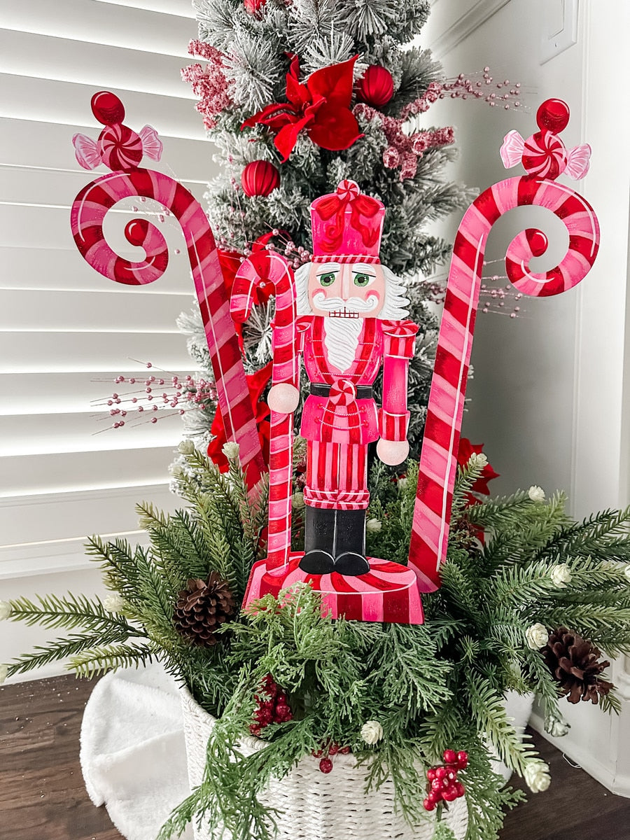Pinkmas Candy Cane stake ornament with red and white striped pattern on a pink background.