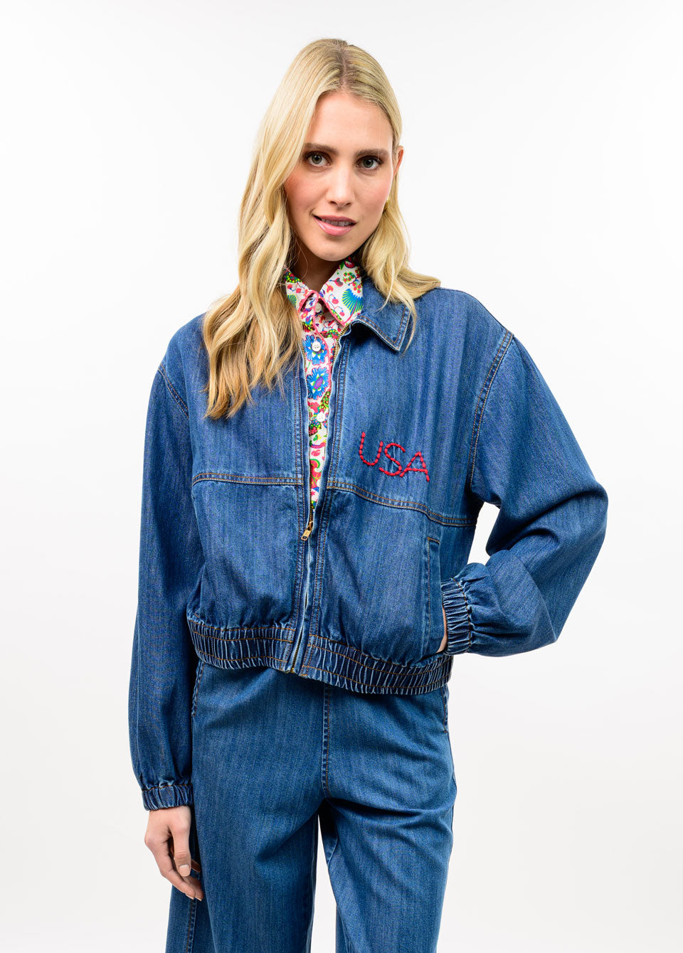 Woman wearing the Avery Denim Flag Embroidery Bomber Jacket with red USA lettering.