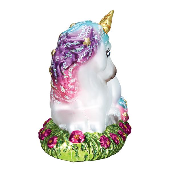Baby unicorn glass ornament with a purple glitter mane sitting on a bed of pink flowers.