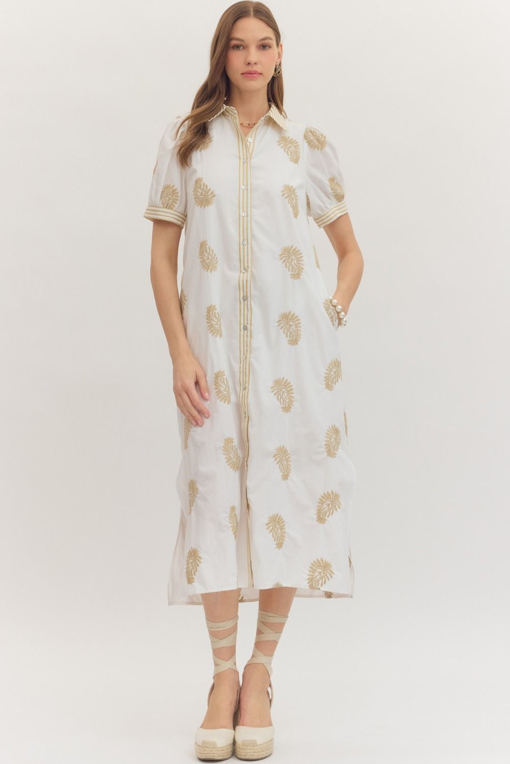 Woman wearing a white Nicole midi dress with gold embroidery and short puff sleeves.