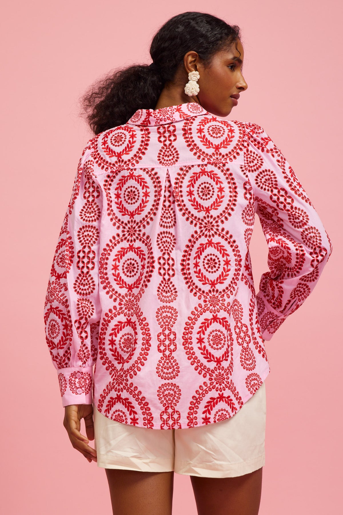 Back view of a pink long-sleeve button-down shirt with red circular eyelet embroidery.