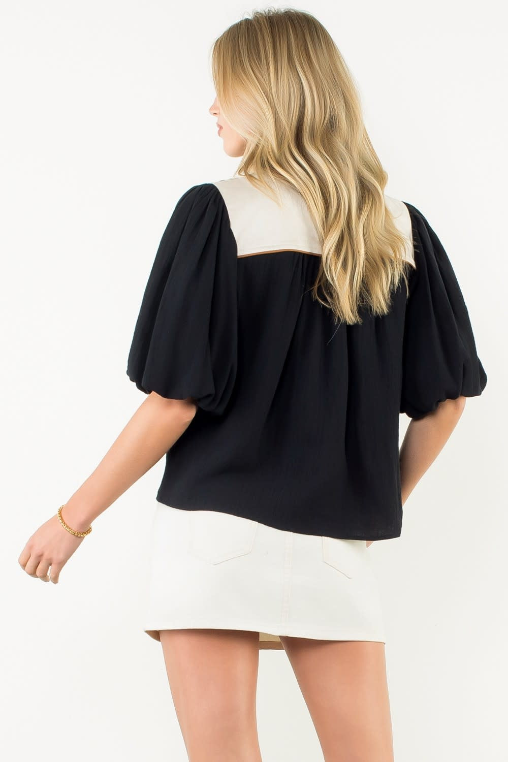 Back view of a white cotton top with puff sleeves and an embroidered neckline.