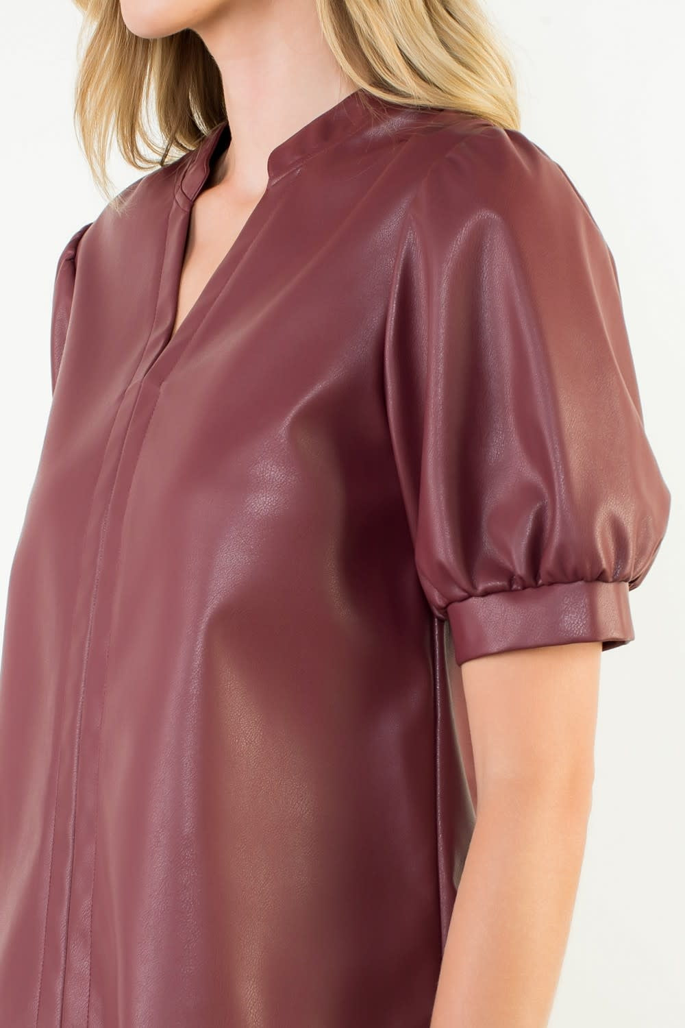Side view of a burgundy woven leather top with puff sleeves and structured silhouette.