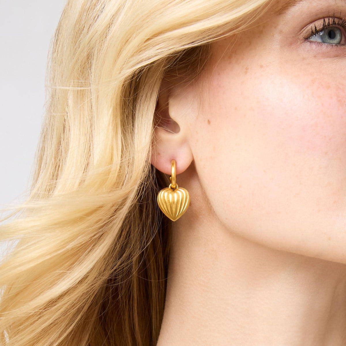 Gold plated puffy heart hoop earring with fluted charm detail