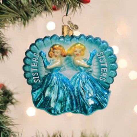 Sisters Sisters Ornament in white ceramic with gold glitter finish featuring two silhouetted figures holding hands.