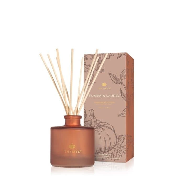 Petite reed diffuser bottle with creamy pumpkin liquid, cinnamon-colored glass, and dark wood sticks.