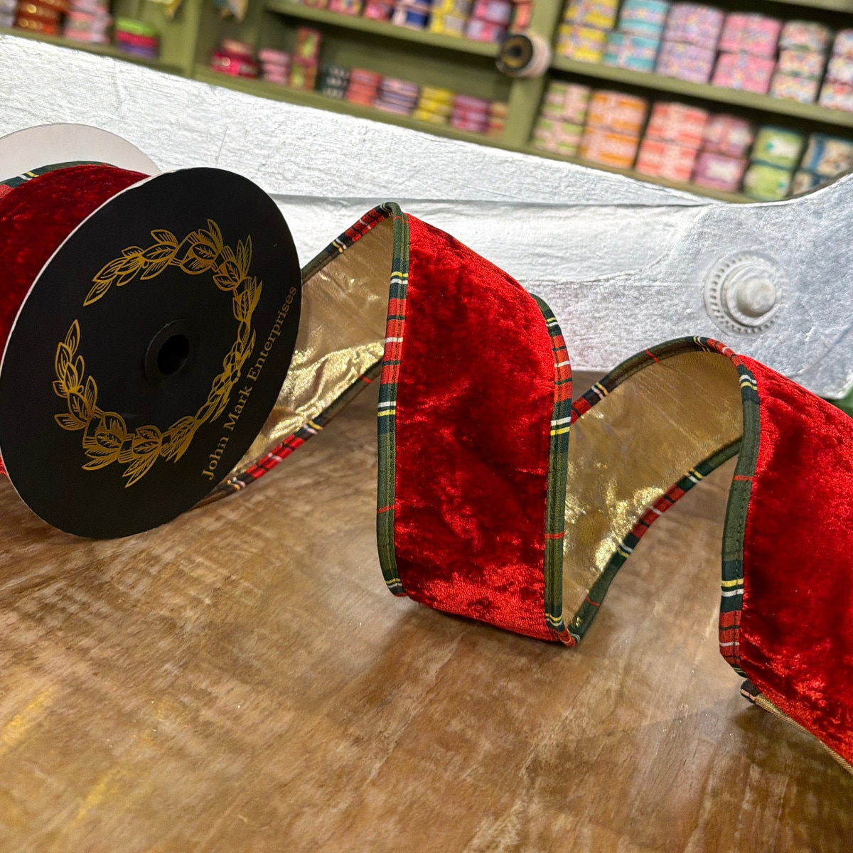 2.5 inch red velvet ribbon with metallic gold backing and plaid piping on a black spool.