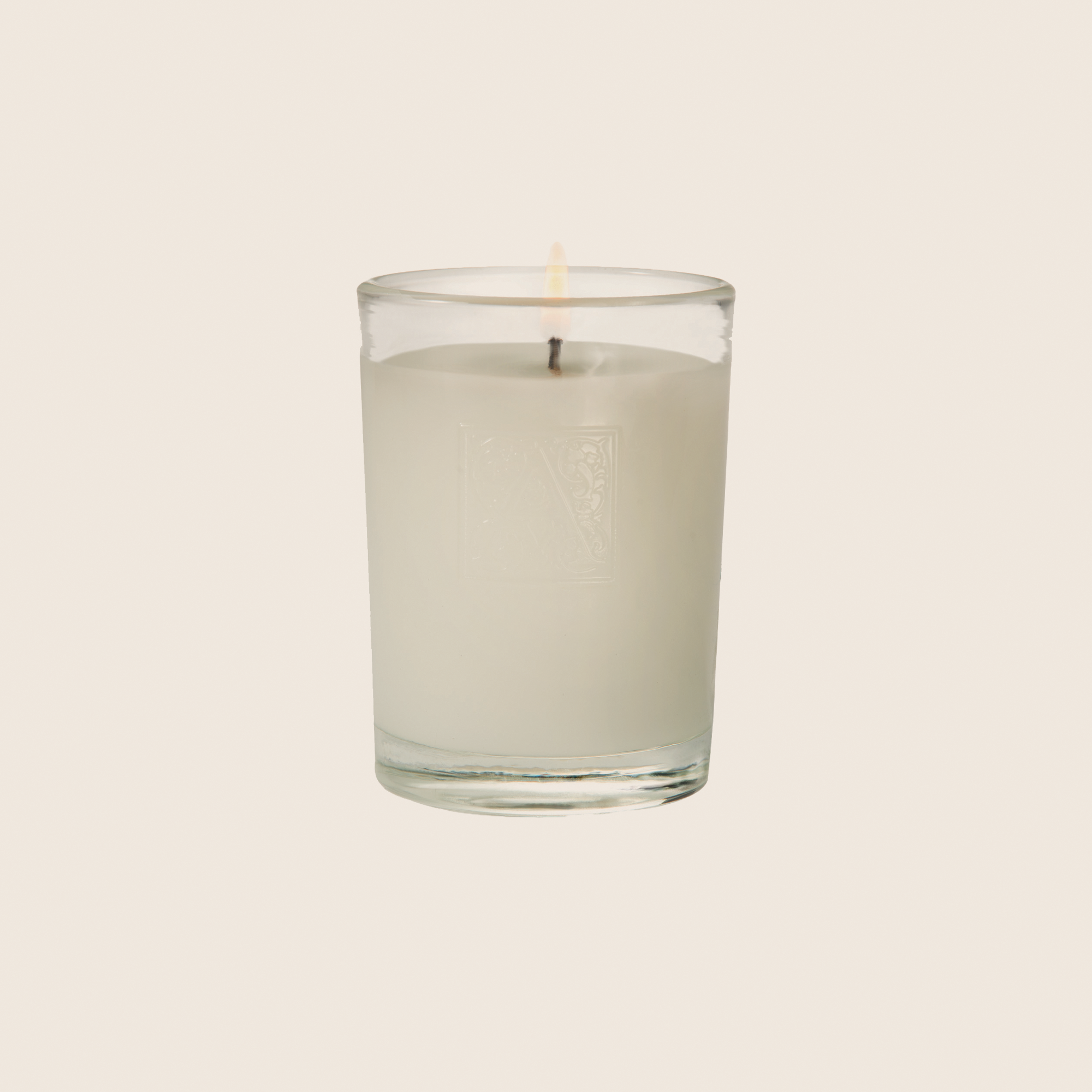 Clear glass cylinder votive candle with white wax in The Smell of Spring fragrance featuring pineapple and floral notes.