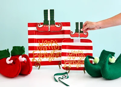Jingle Elf Boots Mini Attachment being placed on a red and white striped Happy Everything! plate.