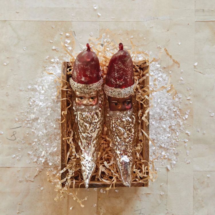 Two mercury glass Santa moon ornaments with red hats and glitter beards in a wooden box.