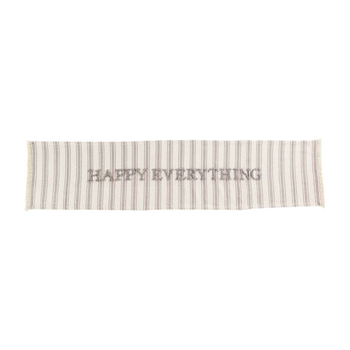 Happy Everything cotton table runner with a colorful geometric patchwork pattern in red, blue, yellow, and green.