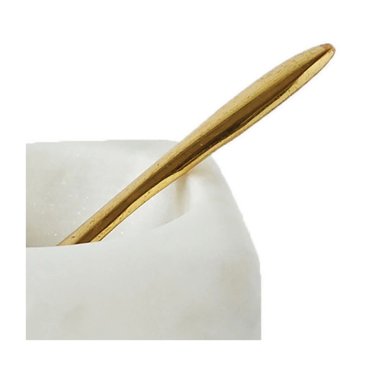 Close-up of a gold-toned brass spoon resting inside a white marble bowl.