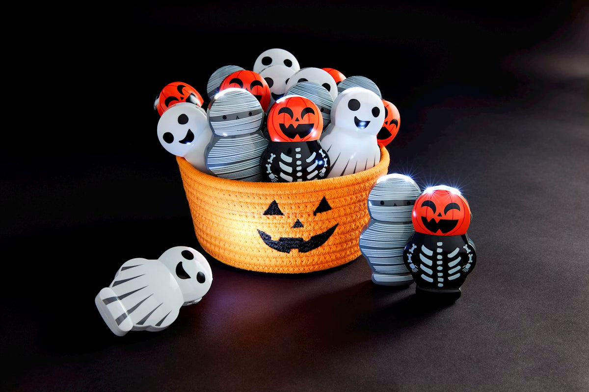 Halloween musical flashlights shaped like ghosts, mummies, and skeletons in an orange pumpkin basket.