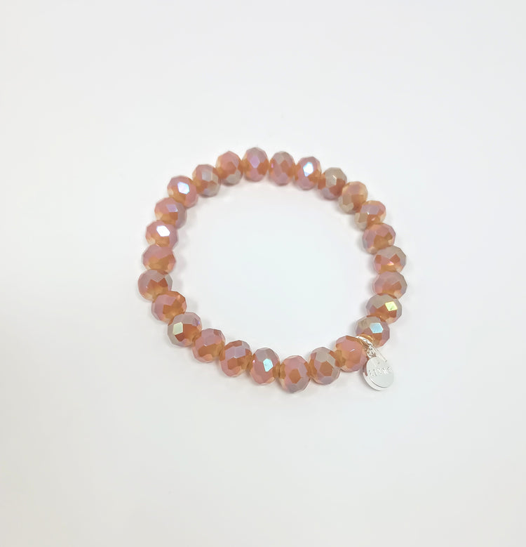 Stretchy bracelet with faceted peach glass beads and a small silver logo charm.