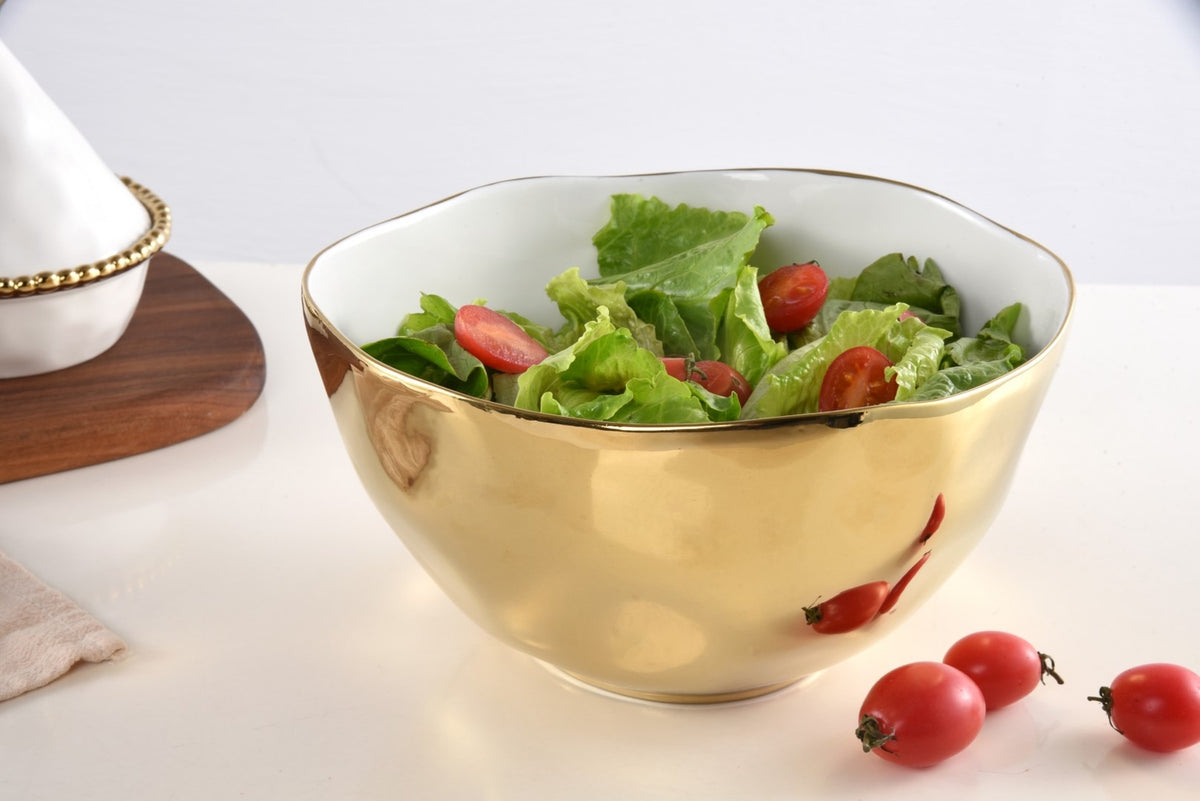 Large gold titanium porcelain bowl filled with fresh green salad and cherry tomatoes.