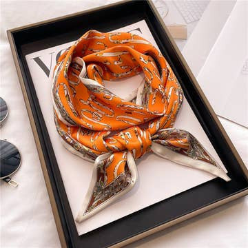 Orange double-layer head scarf with a white and brown pattern, folded on a white magazine.