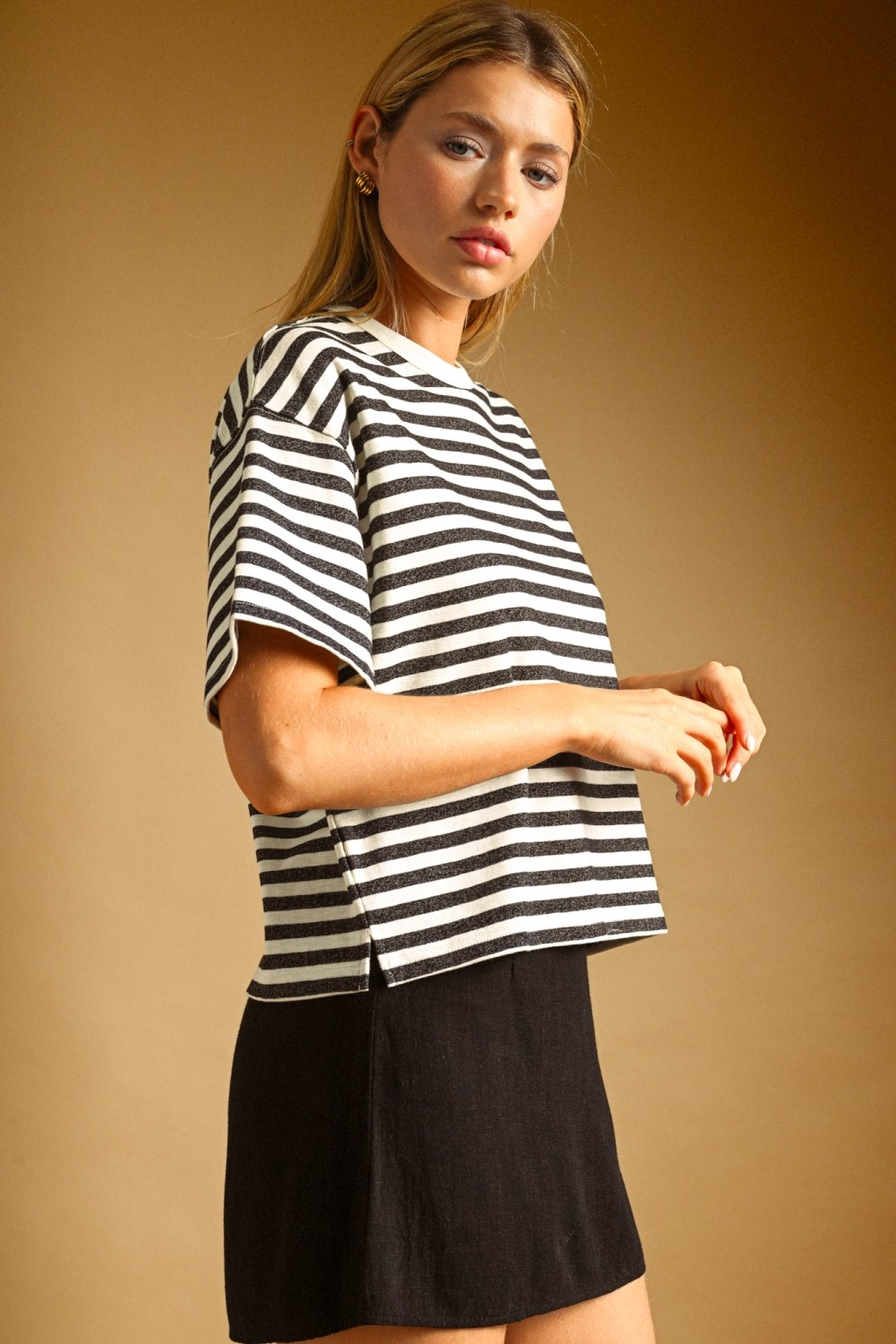 Woman wearing a boxy, oversized black and white horizontal striped short sleeve top.