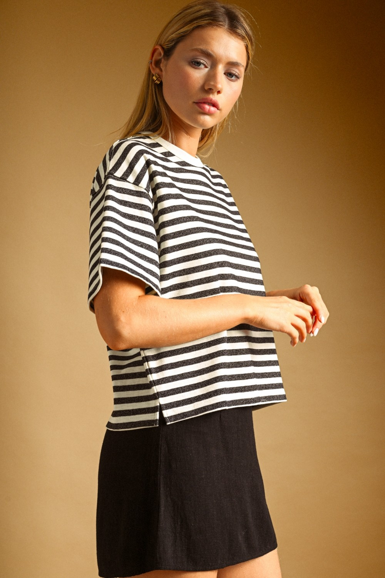Woman wearing a boxy, oversized black and white horizontal striped short sleeve top.